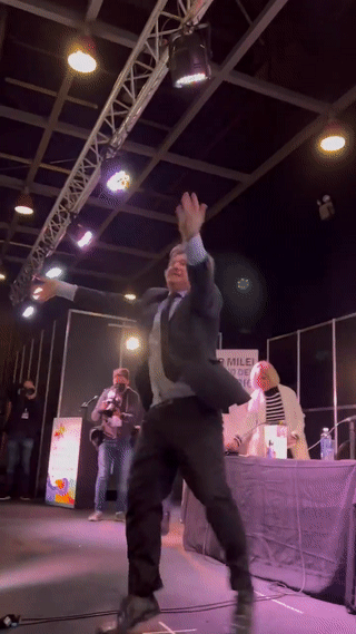 خافيير ميلي يصعد على خشبة المسرح ويظهر بجواره رجل يحمل شوفار ويرتدي شال صلاة يهودي، أغسطس 2023